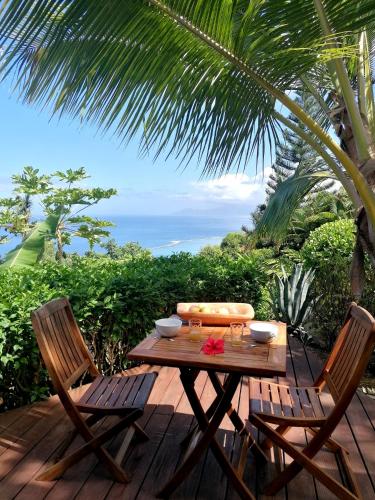 una mesa y dos sillas en una terraza con vistas al océano en Bungalow Moemoea, en Punaauia
