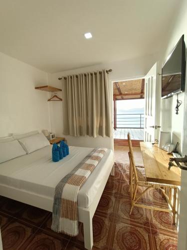a bedroom with a large white bed and a desk at La Sirenne Inn in El Nido