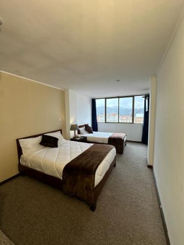 a hotel room with two beds and a large window at Hotel Presidente by NASS in Cuenca