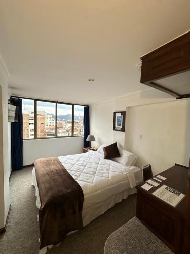 a bedroom with a large bed and a large window at Hotel Presidente by NASS in Cuenca