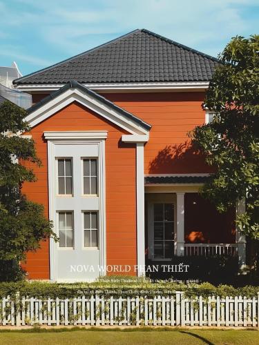an orange and white house with a fence at Holiday Villa Novaworld Phan Thiet in Phan Thiet