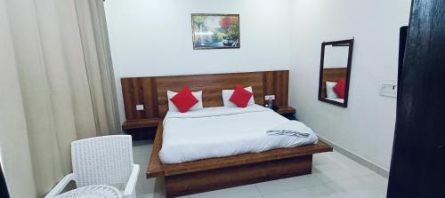 a bedroom with a bed with red pillows and a mirror at The Grace Residency in Gurgaon