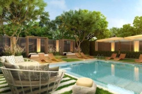 a swimming pool in a yard with chairs and trees at Sukhumwit Soi 10 at VENiO in Khlong Toei
