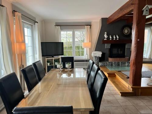 uma sala de jantar com uma mesa de madeira e cadeiras pretas em Spacious villa with private pool in Theux em Theux