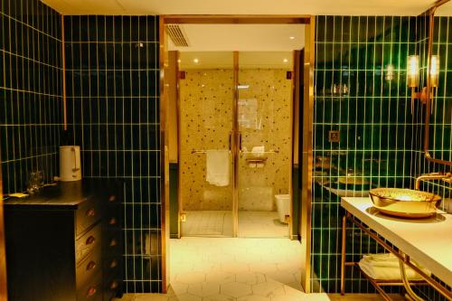 baño con paredes de azulejos verdes y ducha. en Xinyu Hotel - Shanghai Jiao Tong University Xinhua Road, en Shanghái