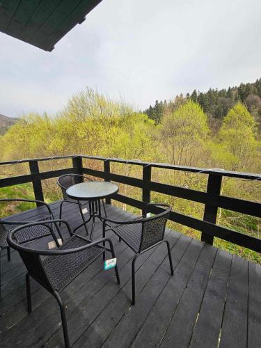 a patio with two chairs and a table on a deck at Симфонія біля річки Чан in Skole