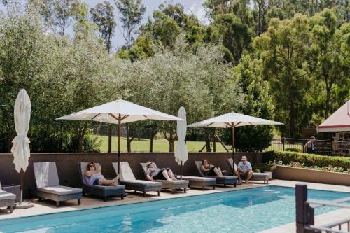 a group of people sitting on lounge chairs next to a pool at Araluen Boutique Accommodation in Yarra Glen