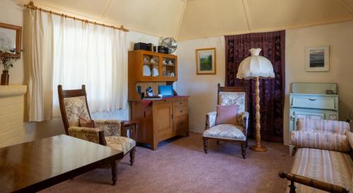 uma sala de estar com uma mesa, cadeiras e um candeeiro em Fernbrook Cottage em Marrangaroo
