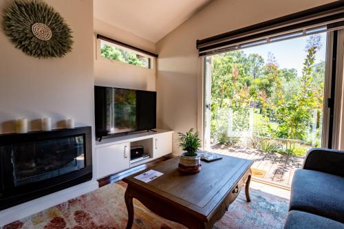 a living room with a tv and a large window at Araluen Boutique Accommodation in Yarra Glen