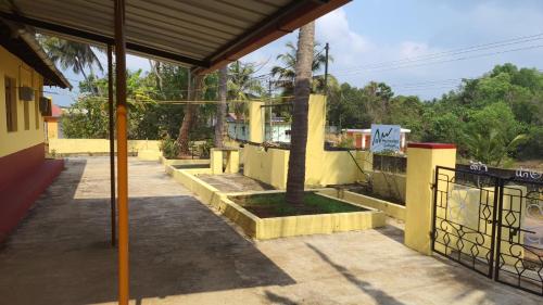 a yellow building with a gate and a tree at Hallimane Homestay in Udupi