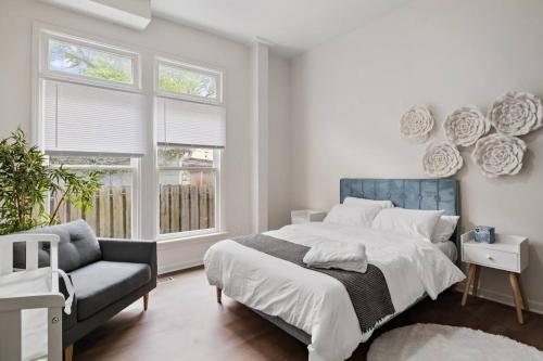 a bedroom with a bed and a chair and windows at Modern Apt - Downtown Charm - Ideal Location in Indianapolis