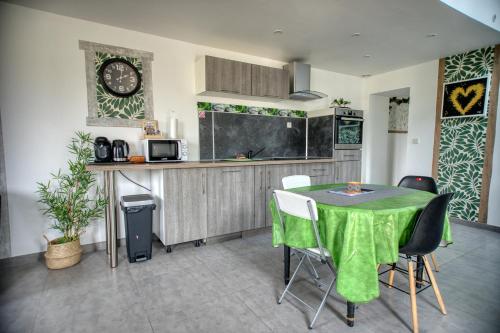 une cuisine avec une table, des chaises et une horloge murale dans l'établissement charmante Maison de campagne, à Biaches