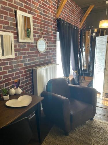 a living room with two chairs and a table and a brick wall at Chaleureux in Villiers-en-Lieu