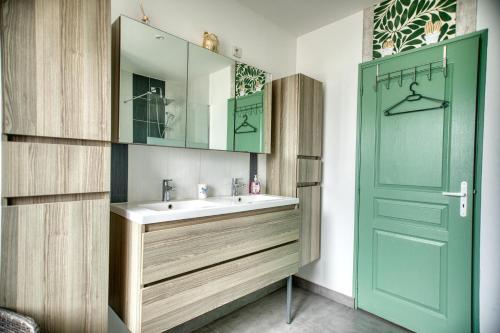 baño con lavabo y puerta verde en charmante Maison de campagne, 