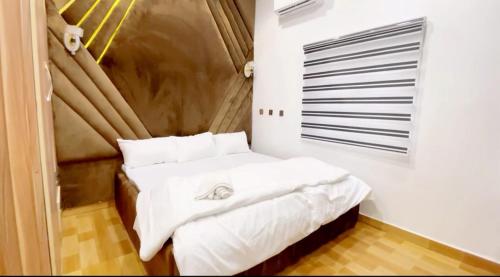 una camera da letto con letto, lenzuola e cuscini bianchi di CEO HOMES AND APARTMENT a Warri