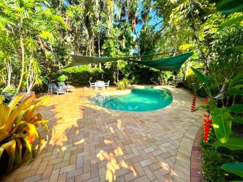 un patio trasero con piscina y hamaca en Aquatica - Luxe Holiday Home en Palm Cove