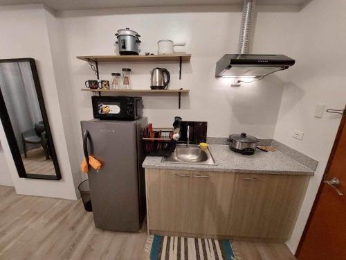 a kitchen with a refrigerator and a counter top at Comfy unit with fast wifi along Lacson St. in Bacolod