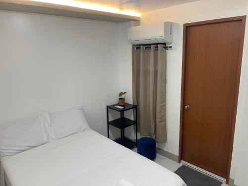 - une chambre avec un lit blanc et une porte marron dans l'établissement SHOWMECAS Alley Stay, à Tagbilaran