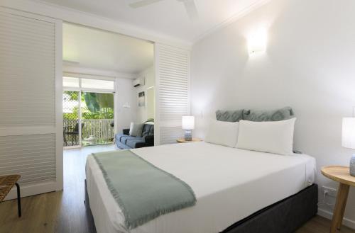 a bedroom with a large white bed and a balcony at Ocean Palms Apartments in Port Douglas