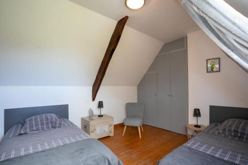 a attic bedroom with two beds and a chair at Gite de Kerigochen - Kraou Tomm in Saint-Igeaux