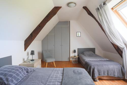 a attic bedroom with two beds and a chair at Gite de Kerigochen - Kraou Tomm in Saint-Igeaux