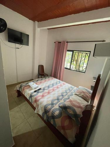 een slaapkamer met een bed, een raam en een televisie bij Hostal MONARCA in Jamundí