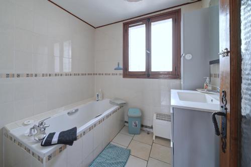 un bagno bianco con vasca e lavandino di La Maison du Village a Encausse-les-Thermes