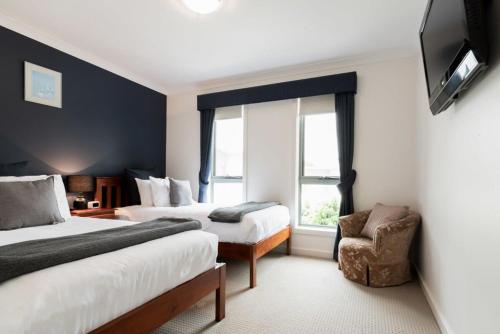 een hotelkamer met 2 bedden en een stoel bij Comfortable Home 10 Minutes from Town - Wifi and Garage in Newnham