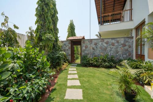 a garden with a stone wall and a walkway at SaffronStays Niranta- 4-BDR villa on golf course near Bangalore in Bengaluru
