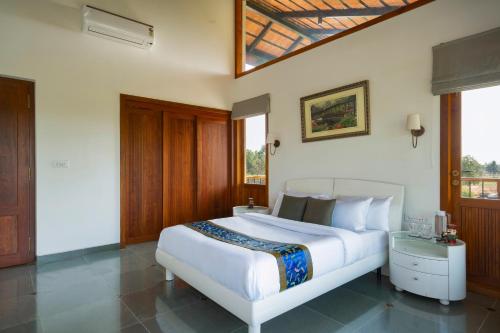 a bedroom with a large white bed and some windows at SaffronStays Niranta- 4-BDR villa on golf course near Bangalore in Bengaluru