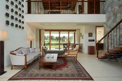 a living room with couches and a table at SaffronStays Niranta- 4-BDR villa on golf course near Bangalore in Bengaluru