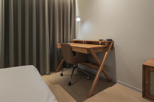 a desk with a chair in a room with a bed at Aank Hotel Incheon Guwol in Incheon