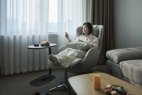 a woman sitting in a chair in a living room at Aank Hotel Incheon Guwol in Incheon