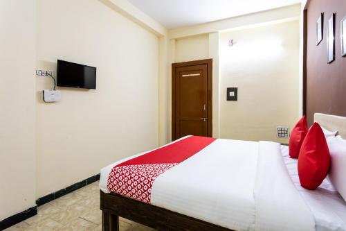 a bedroom with a bed with red pillows and a tv at Hotel Santushti in Dewās