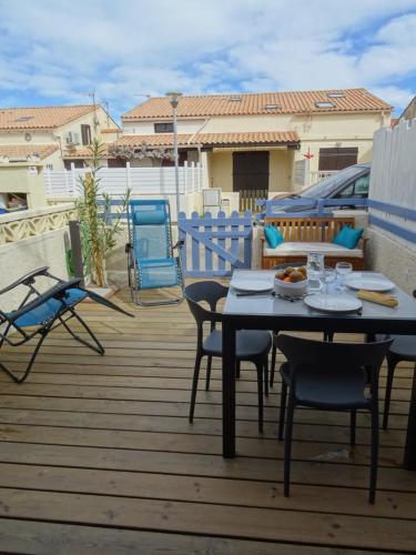 un patio avec une table et des chaises sur une terrasse dans l'établissement Maison près des plages, à Port-la-Nouvelle