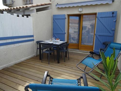 un patio avec une table et des chaises sur une terrasse dans l'établissement Maison près des plages, à Port-la-Nouvelle