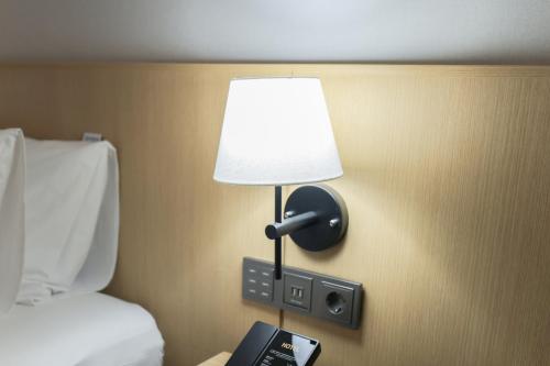 uma lâmpada numa parede ao lado de uma cama em Aank Hotel Incheon Guwol em Incheon