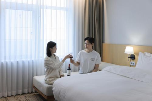 Ein Mann und eine Frau sitzen neben einem Bett in der Unterkunft Aank Hotel Incheon Guwol in Incheon