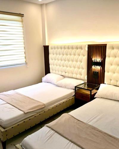 a bedroom with two beds and a table and a window at The farmhouse villa beach resort in Morong