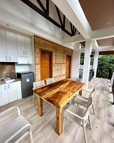 a kitchen with a wooden table and white chairs at The farmhouse villa beach resort in Morong
