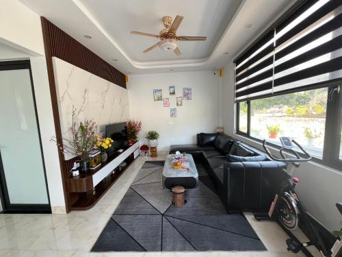 - un salon avec un canapé noir et un ventilateur de plafond dans l'établissement TEELAD VILLA - MỘC CHÂU, à Mộc Châu