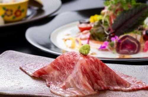 a piece of meat on a table with plates of food at 別邸　たてしな薫風 in Yukawa