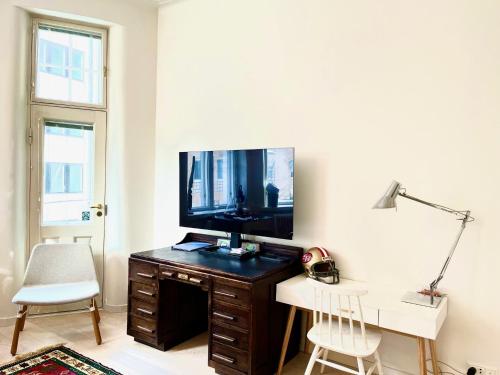 a living room with a television on a wooden desk at Art Nouveau - Jugend Talo in Helsinki Center Apartment in Helsinki