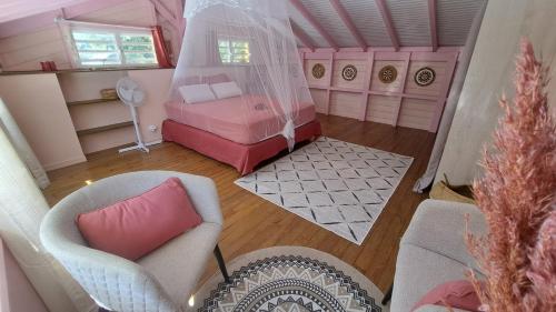 ein Schlafzimmer im Puppenhaus mit einem rosa Bett und einem Stuhl in der Unterkunft La libellule caribéenne in Sainte-Rose