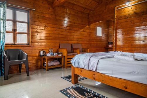 a bedroom with a bed and a desk and a chair at Leo wooden resorts in Hampi