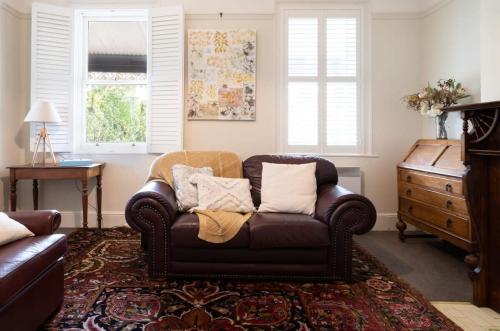 a living room with a brown couch and a dresser at Charming On Charles in Launceston