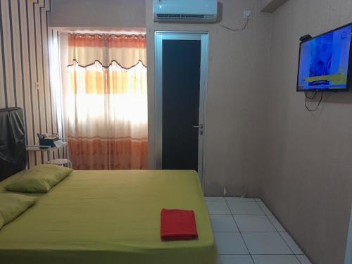 een slaapkamer met een bed en een televisie en een deur bij Apartemen Riverview Sewa Room in Tegalgede