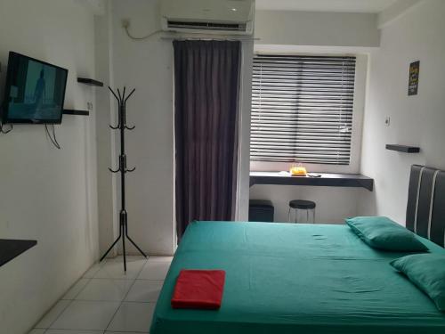 een slaapkamer met een groen bed en een bureau bij Apartemen Riverview Sewa Room in Tegalgede