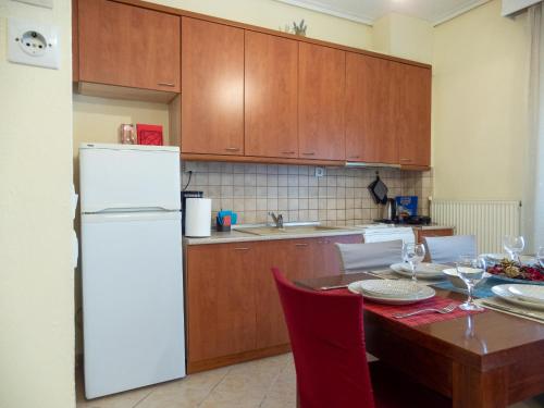 a kitchen with a table and a white refrigerator at The fir trees house - Το σπίτι με τα έλατα in Litochoro