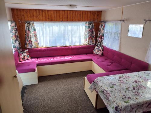 sala de estar con sofá rosa en una habitación en Domki holenderskie HEL, en Hel
